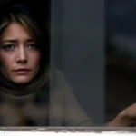 Wenn alles zu viel wird | Eine Frau schaut mit einem müden Ausdruck aus dem Fenster.